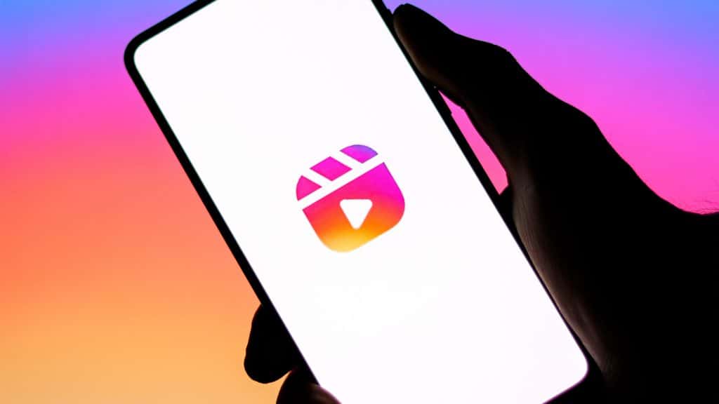 Pessoa segurando celular com logotipo dos Reels do Instagram