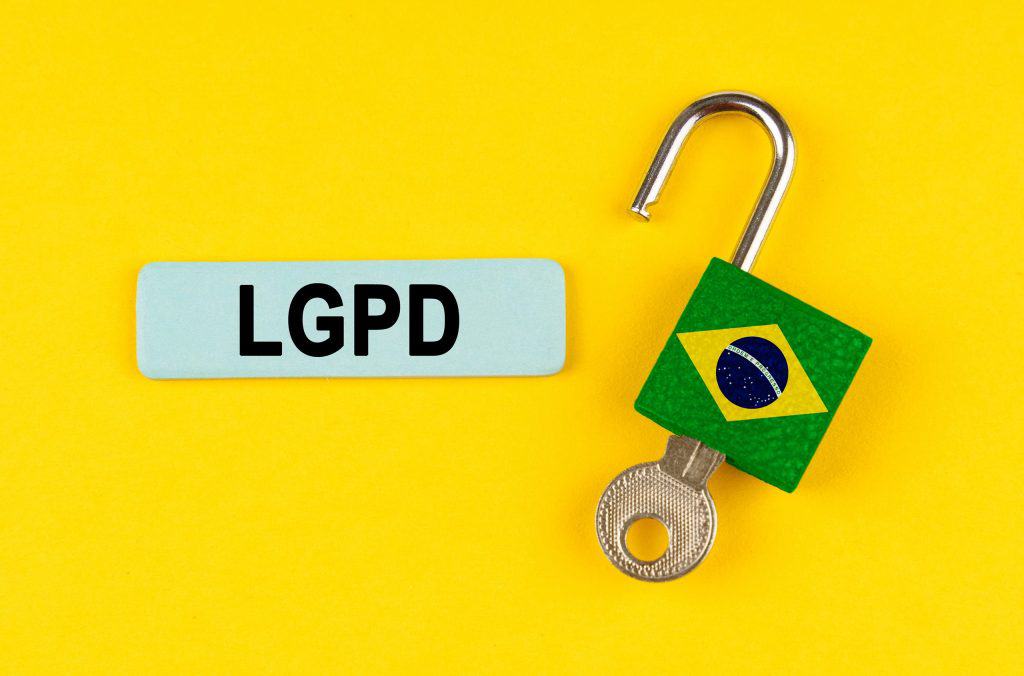 Escrito "LGPD" em fundo amarelo ao lado de um cadeado aberto com a bandeira do Brasil impressa