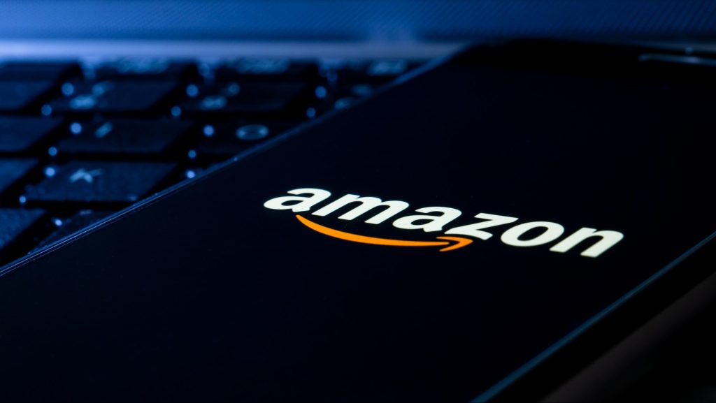 Celular com logomarca da Amazon na tela colocado em cima de teclado de computador