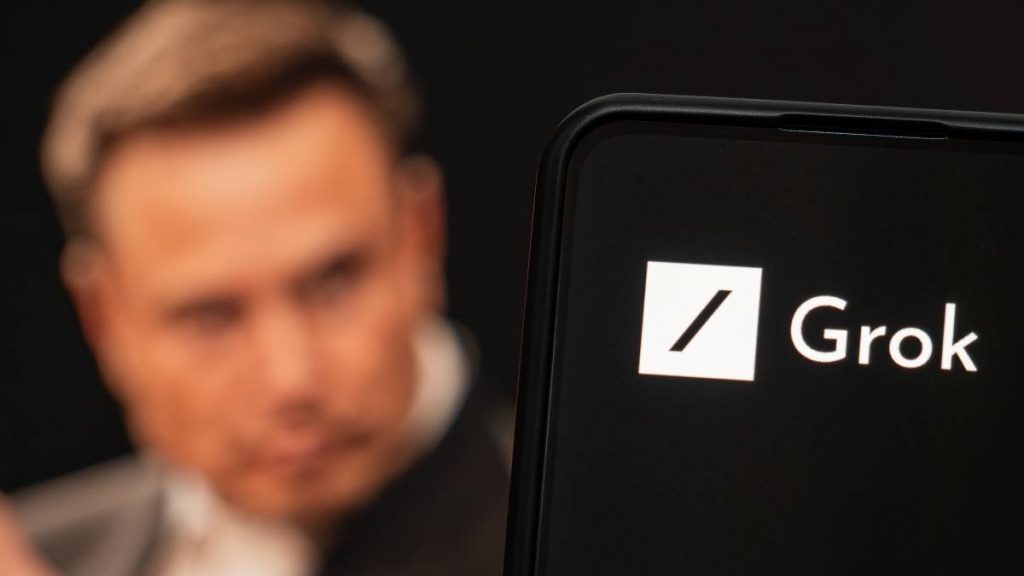 Ao fundo, imagem borrada de Elon Musk; à frente, logo do Grok em um smartphone