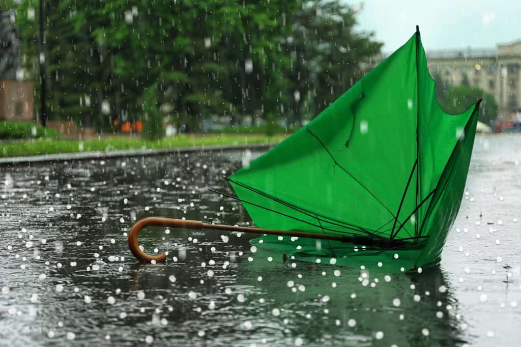 Granizo e um guarda-chuva verde quebrado no chão