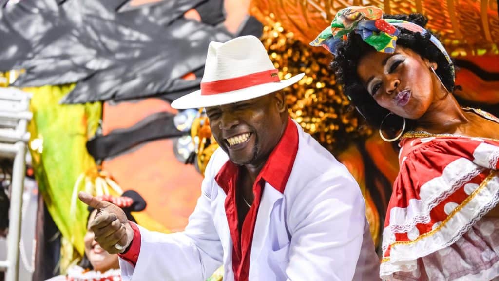 Casal de Porta Bandeira de escola de samba de Rio de Janeiro sorrindo durante o desfile no Sambódromo.