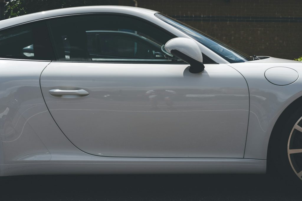 imagem mostra um carro branco, caro e de luxo da marca porsche, estacionado