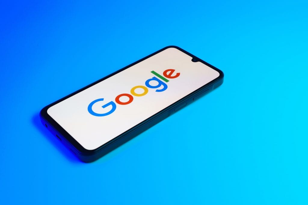 Logo do Google na tela de um smartphone que está em cima de uma superfície azul