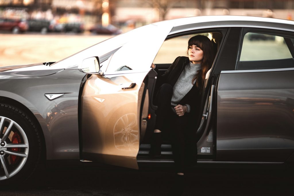 mulher pousando dentro de um carro com a porta aberta