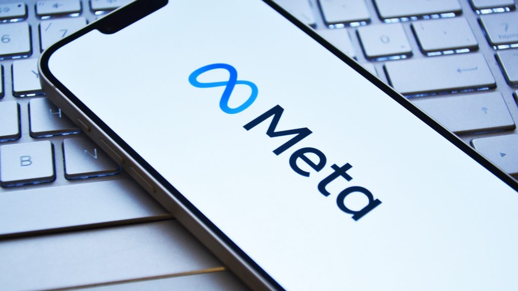 Celular com logomarca da Meta na tela colocado em cima de teclado de notebook