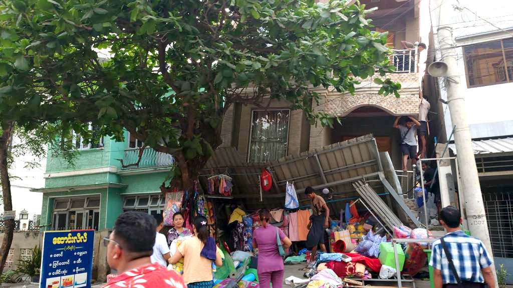 Pessoas perto de prédio danificado por conta de terremoto em Mianmar