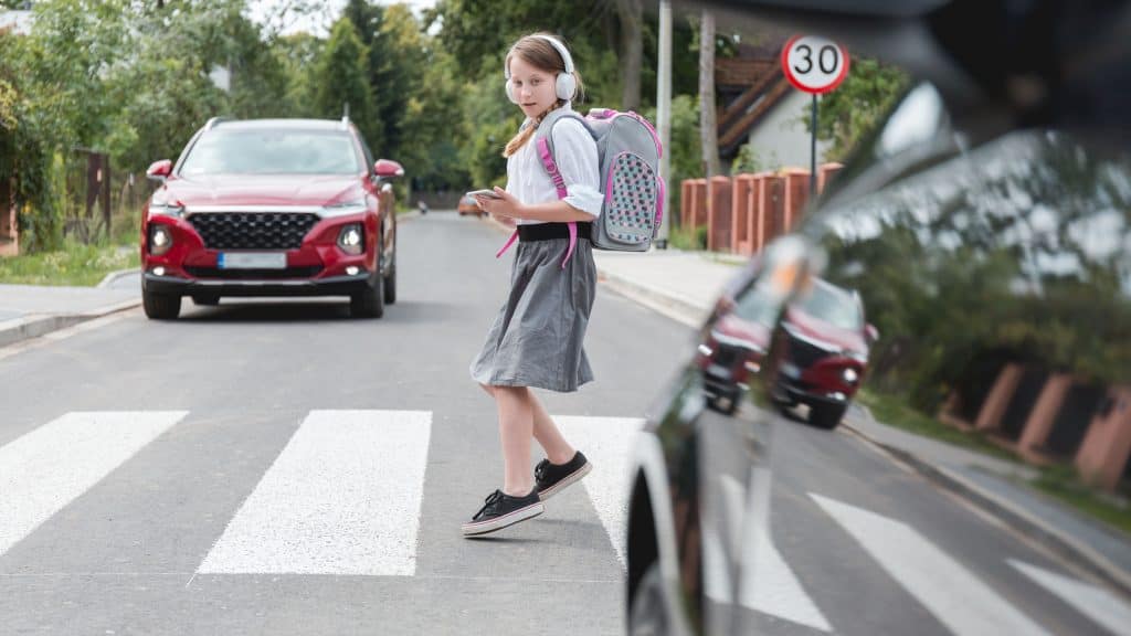 menina atravessando na faixa e um carro se aproximando