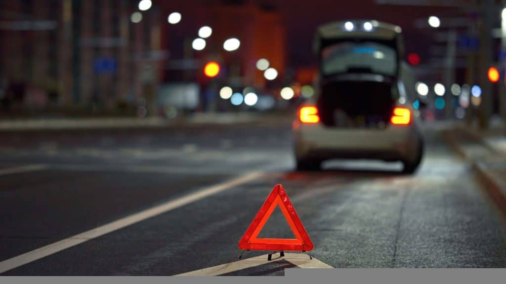 triângulo de sinalização e carro com defeito