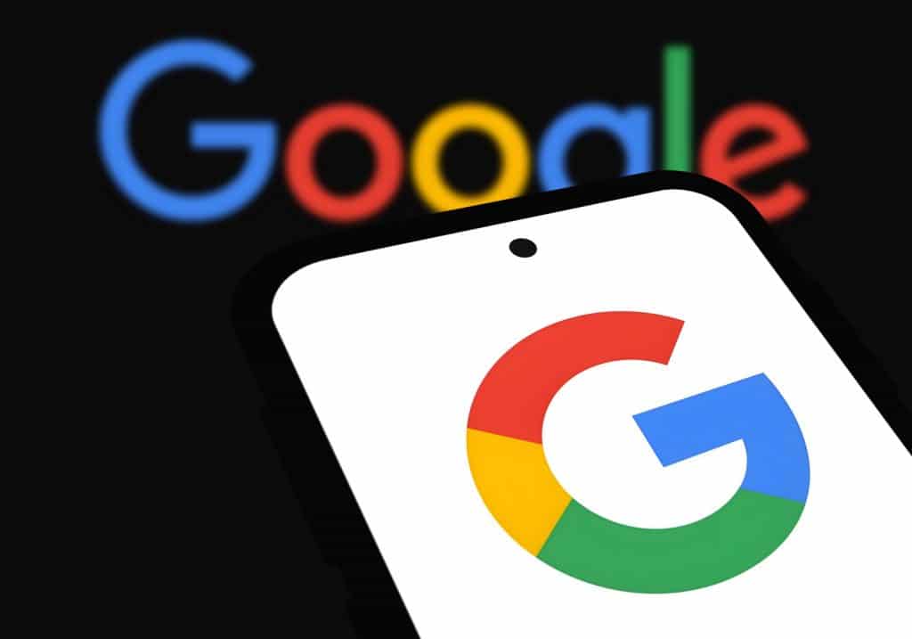 Logo do Google, desfocado, ao fundo; à frente, letra G da empresa estilizada em um smartphone