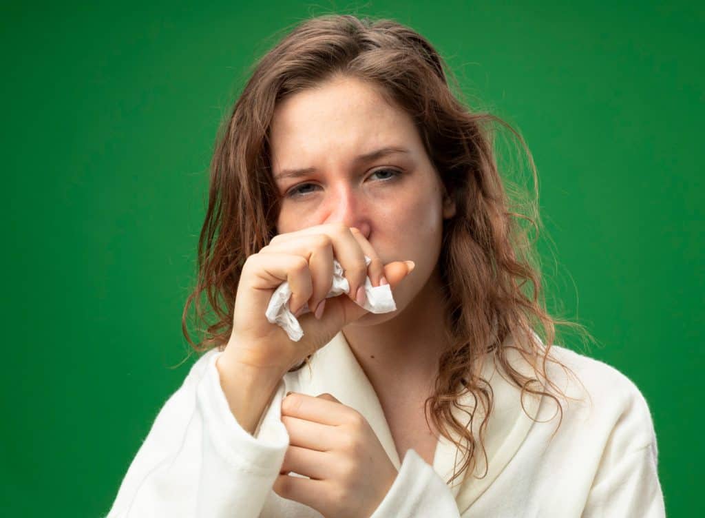 mulher com papel na mão e mexendo no nariz