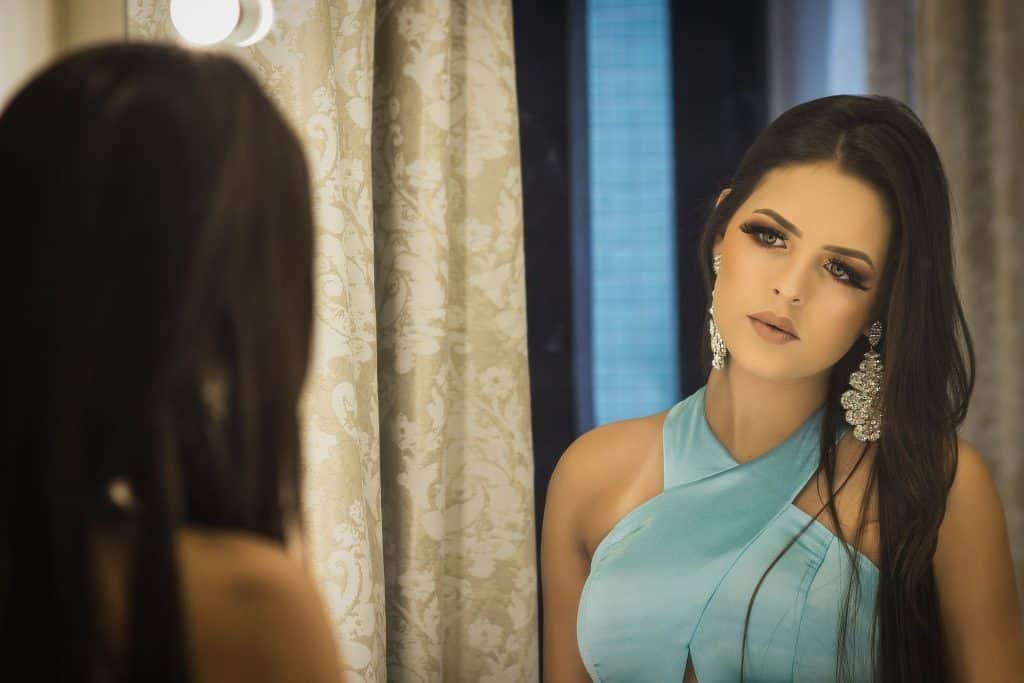 Imagem de mulher pensativa se olhando no espelho