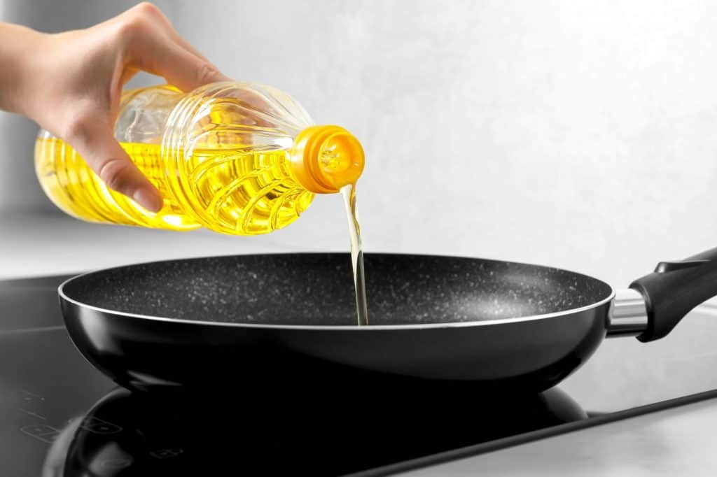 Óleo de cozinha sendo despejado em uma frigideira