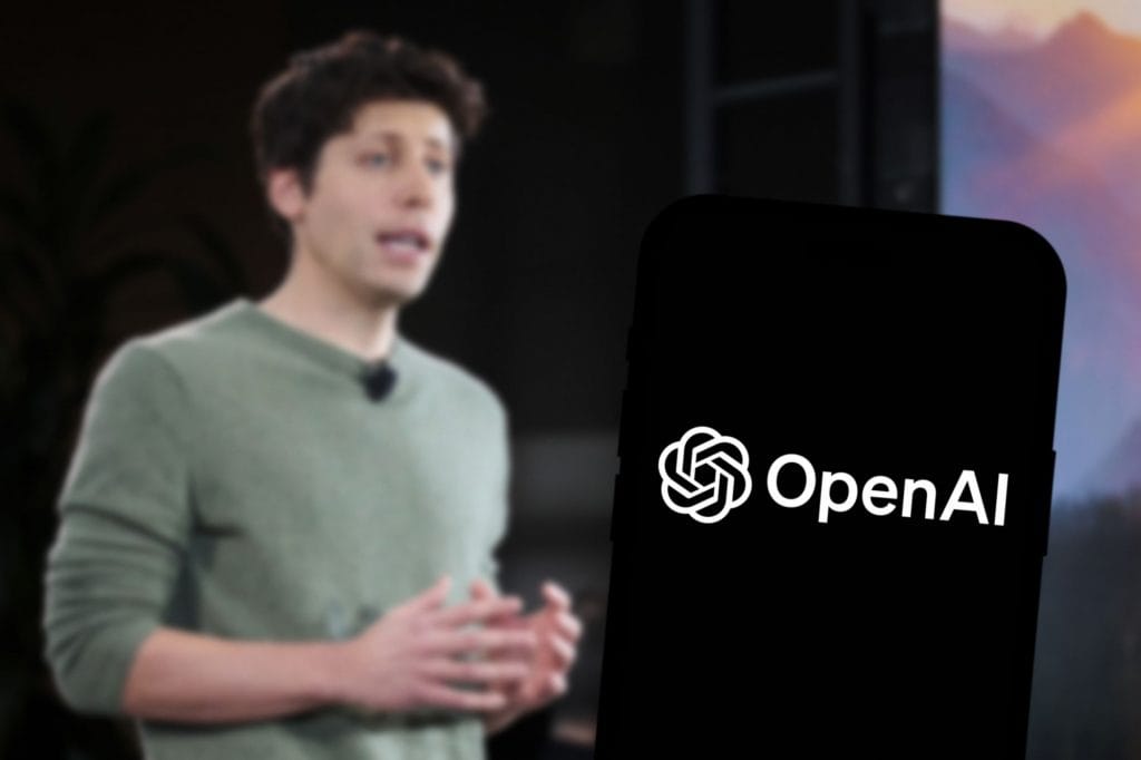 Ao fundo, Sam Altman; à frente, logo da OpenAI na tela de um smartphone