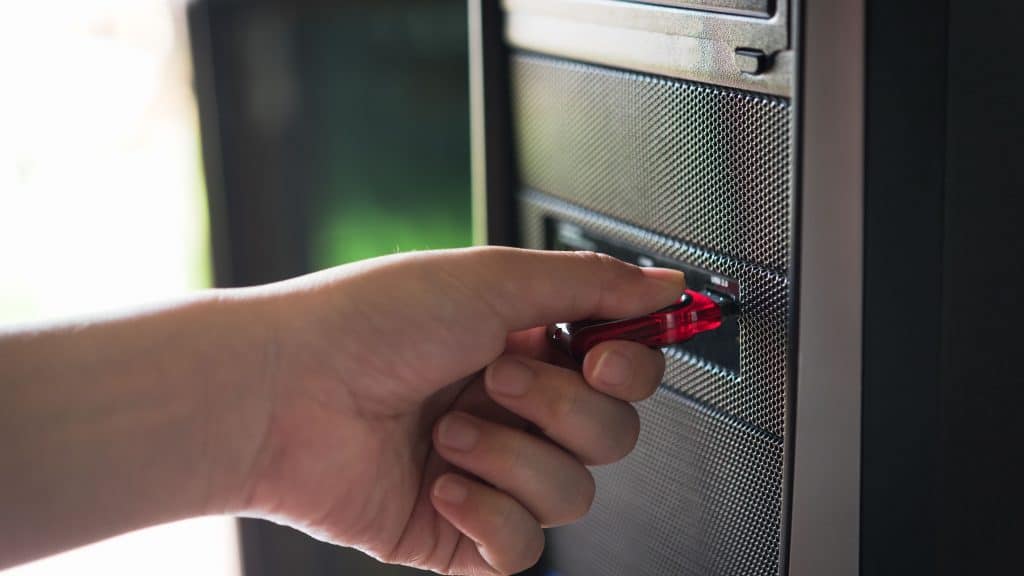 Pessoa inserindo um pendrive na porta USB de um PC
