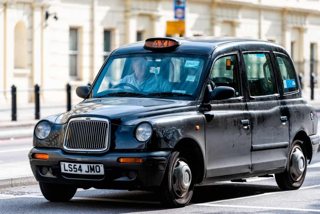 Imagem mostra clássico taxi preto inglês, em que se adota a mão inglesa, com volante do lado direito do carro