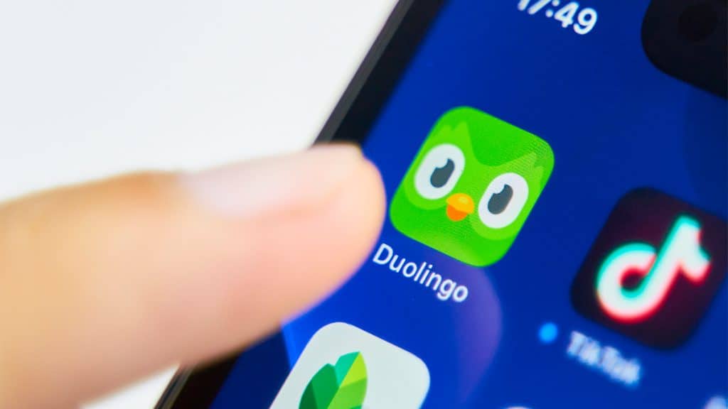 Pessoa com dedo sobre ícone do aplicativo do Duolinguo num iPhone