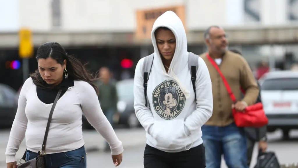 Pessoas andando agasalhadas na rua em dia frio