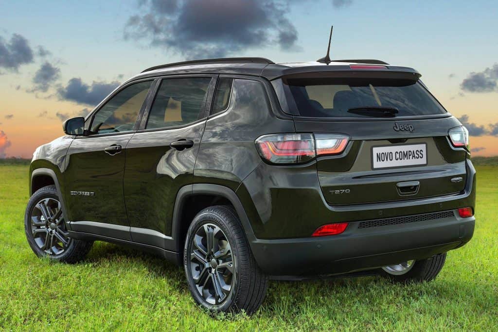 Imagem mostra um carro preto (jeep compass 2024) estacionado na grama