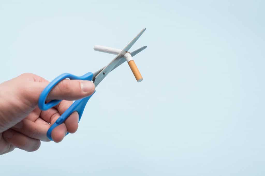 pessoa cortando cigarro com uma tesoura