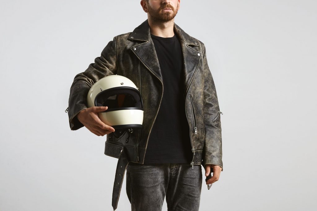 Imagem mostra homem motociclista segurando o capacete de moto