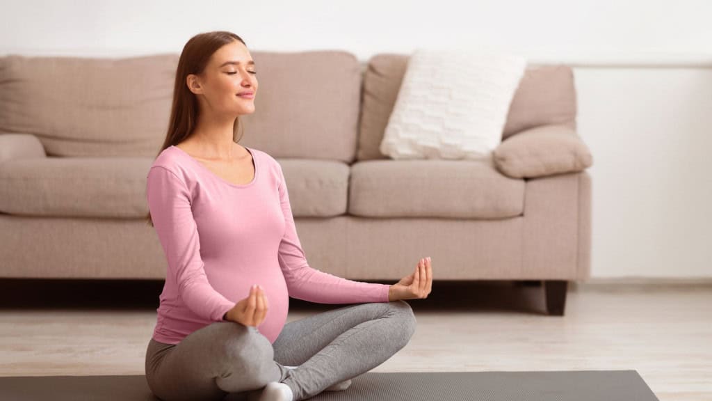 Yoga para grávidas. Linda mulher grávida relaxando, respirando no chão em casa, espaço livre