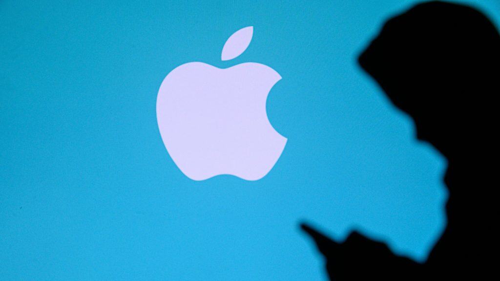 NOVA YORK, EUA, 25 DE MAIO DE 2020: A Apple, empresa multinacional americana de tecnologia, um jovem conversa em um celular. Logotipo da empresa na tela ao fundo.