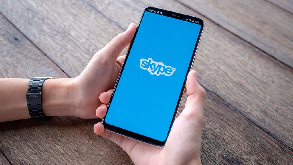 Pessoa segurando celular com logomarca do Skype