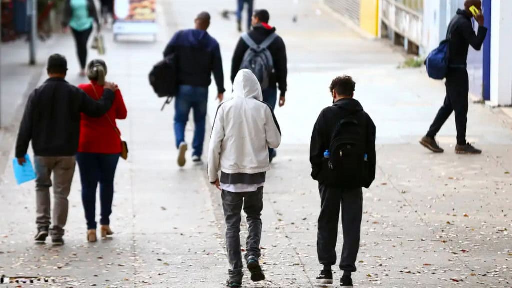 Pessoas andando agasalhadas na rua em dia frio