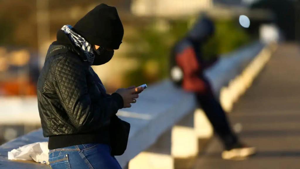 Duas pessoas muito agasalhadas encostadas em mureta durante dia frio