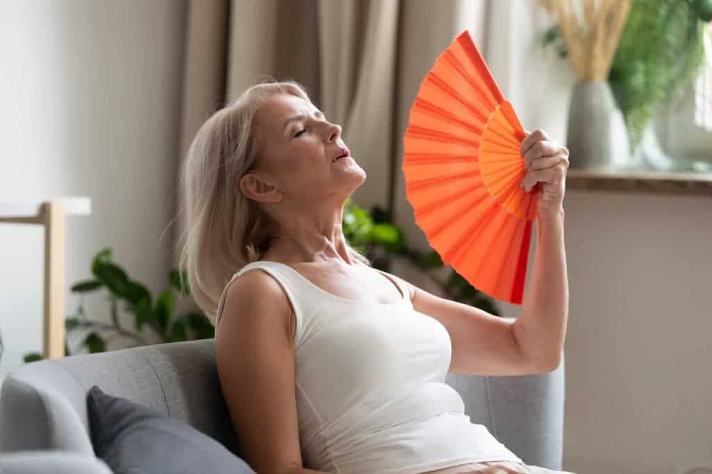 mulher se abanando pelo calor da menopausa
