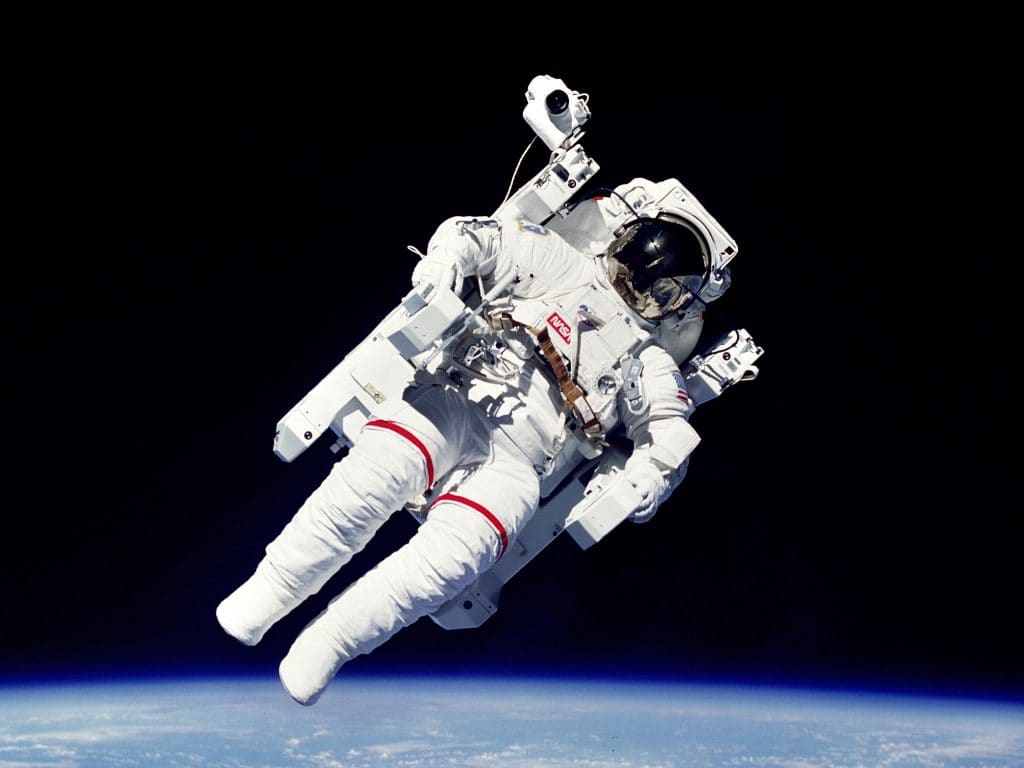 Bruce McCandless II Sobrevoando o planeta terra na primeira caminhada espacial sem cordas de retenção.