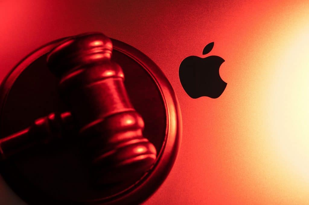 Martelo de juiz em cima de um MacBook, exibindo o logo da Apple ao lado