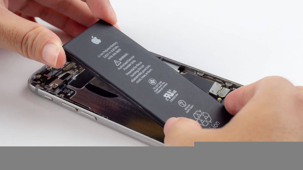 imagem mostra uma pessoa encaixando uma bateria na traseira de um celular