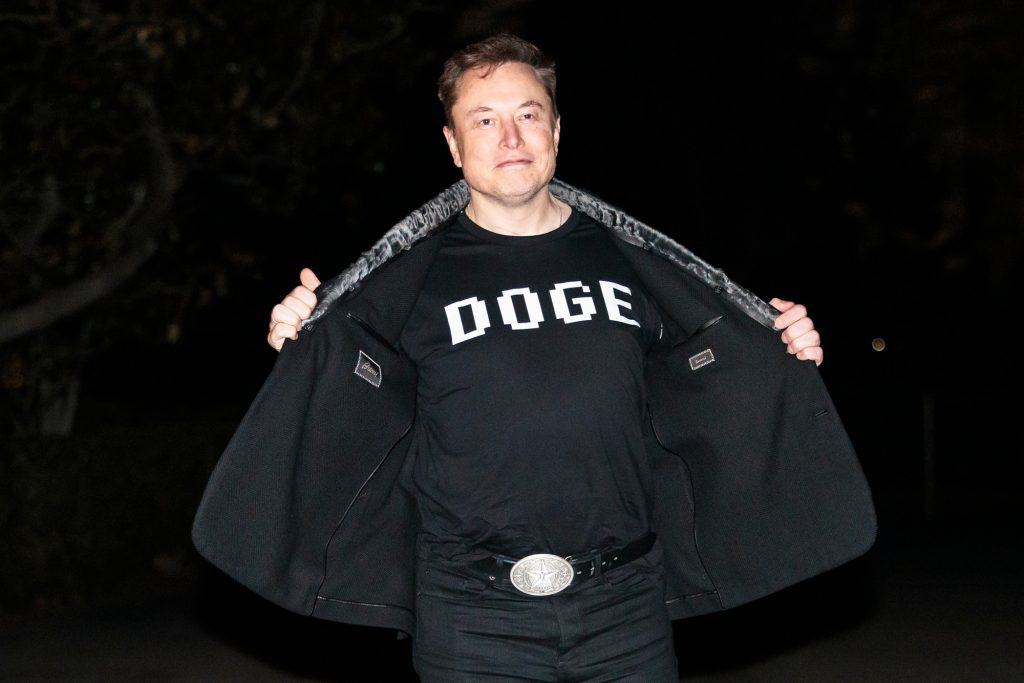 Elon Musk usando uma camiseta com os dizeres "DOGE"