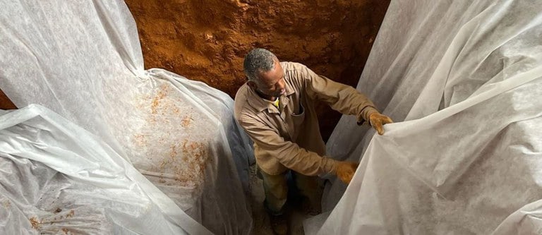 Homem cobrindo as laterais da área escavada