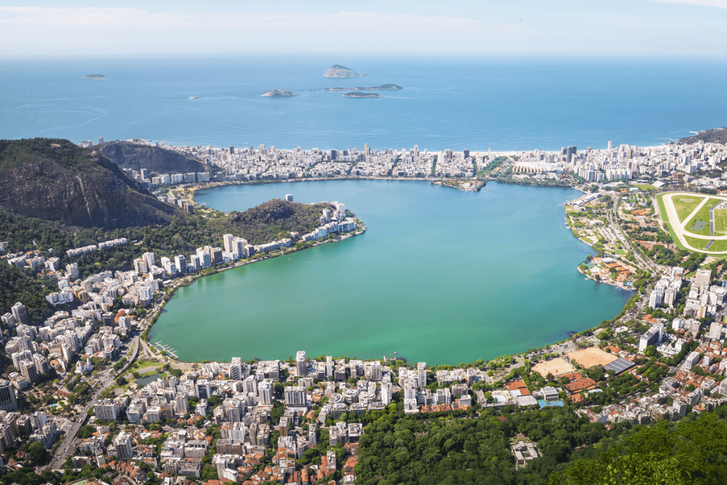 imagem mosta a vista de cima da lagoa rodrigo freitas: a água da lgoa está em dois tons de verde com a cidade do rio ao seu redor