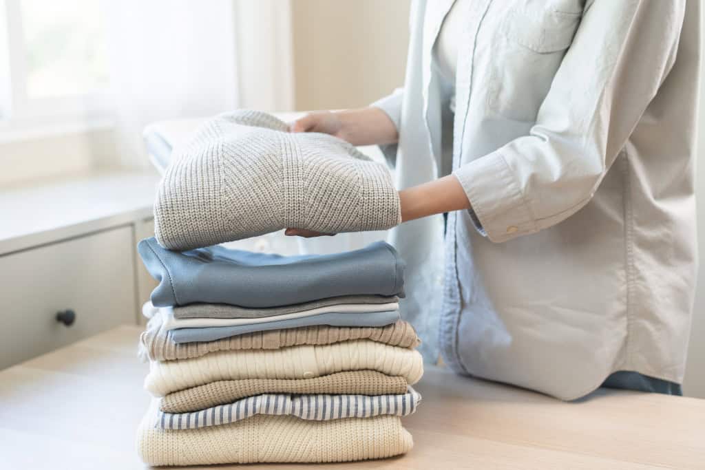 Roupas dobradas, sendo que uma está nas mãos de uma mulher