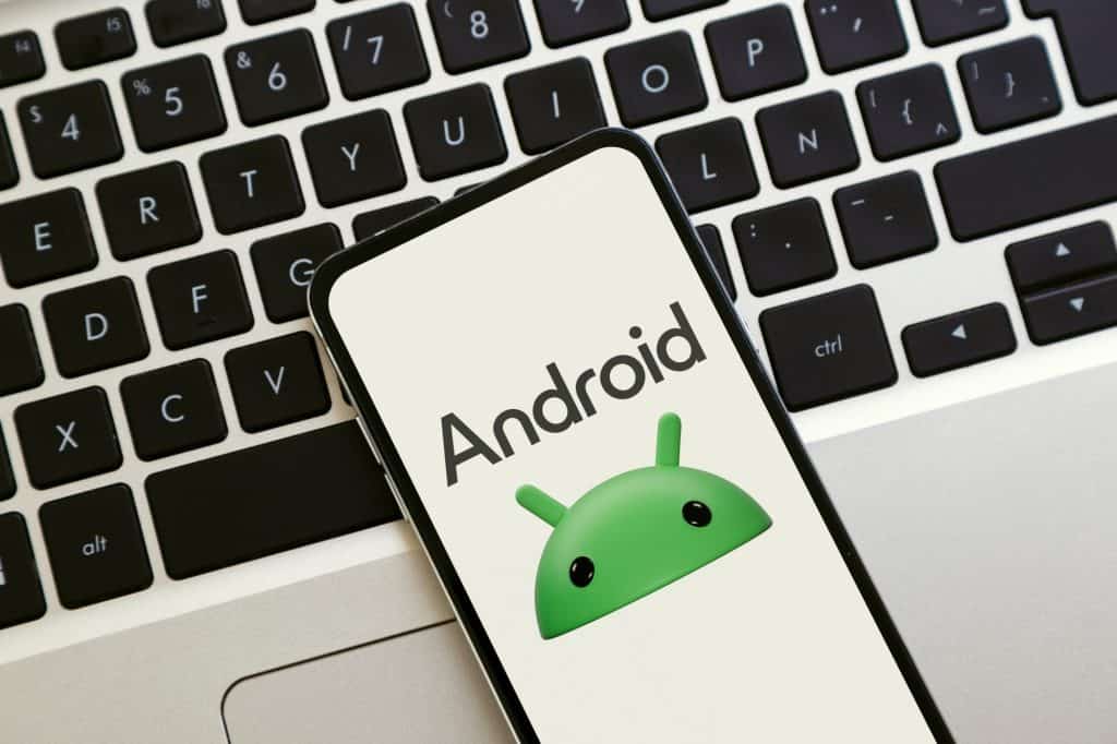 Logotipo do Android na tela do celular. Um smartphone sobre um laptop exibindo o novo logotipo do Android