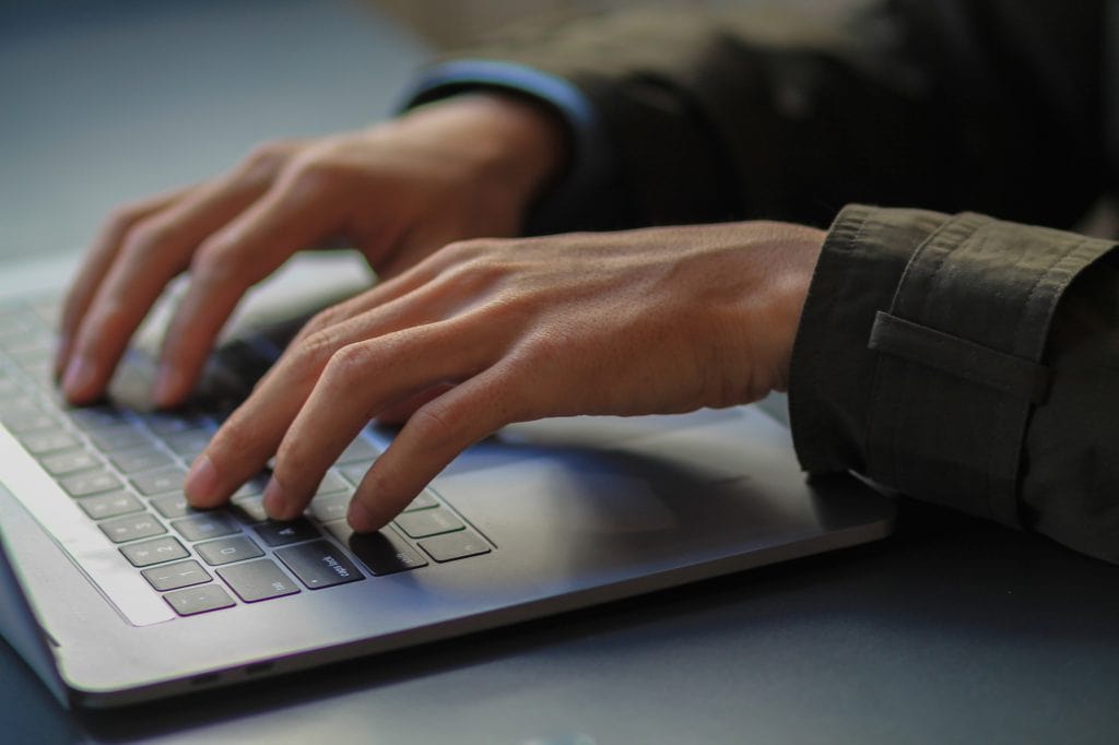 mãos de um homem em teclado de computador