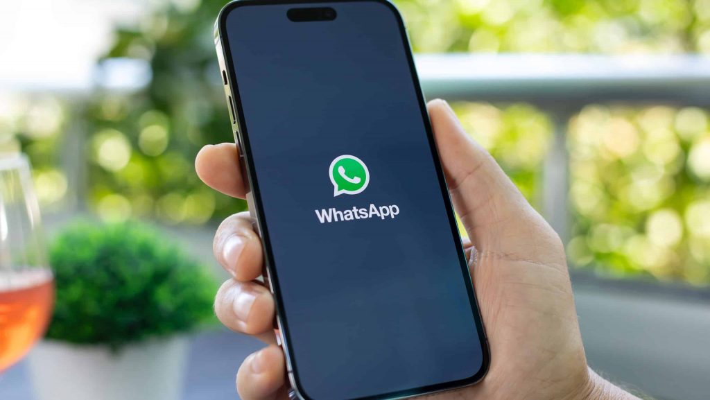 Logo do WhatsApp em um smartphone segurado por uma pessoa