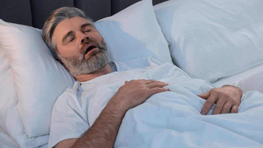 Homem roncando enquanto dorme na cama em casa
