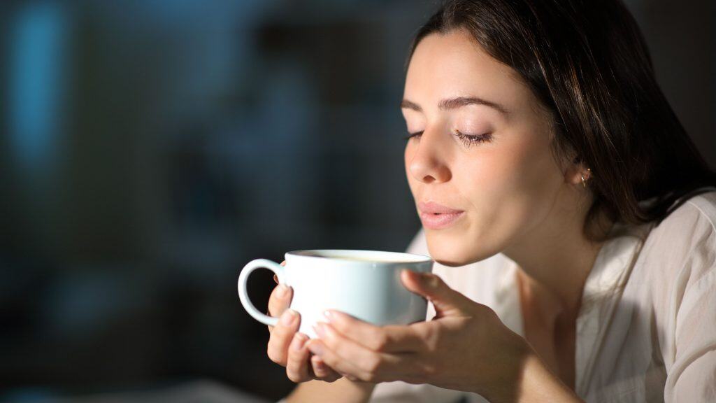 mulher assoprando uma xícara de café