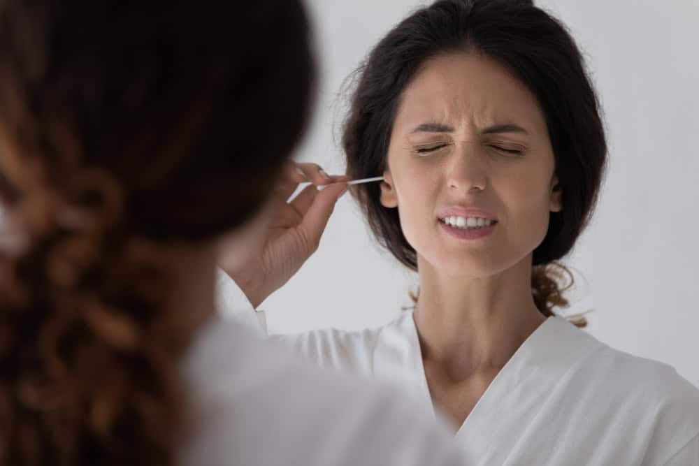 Mulher coçando o ouvido com cotonete