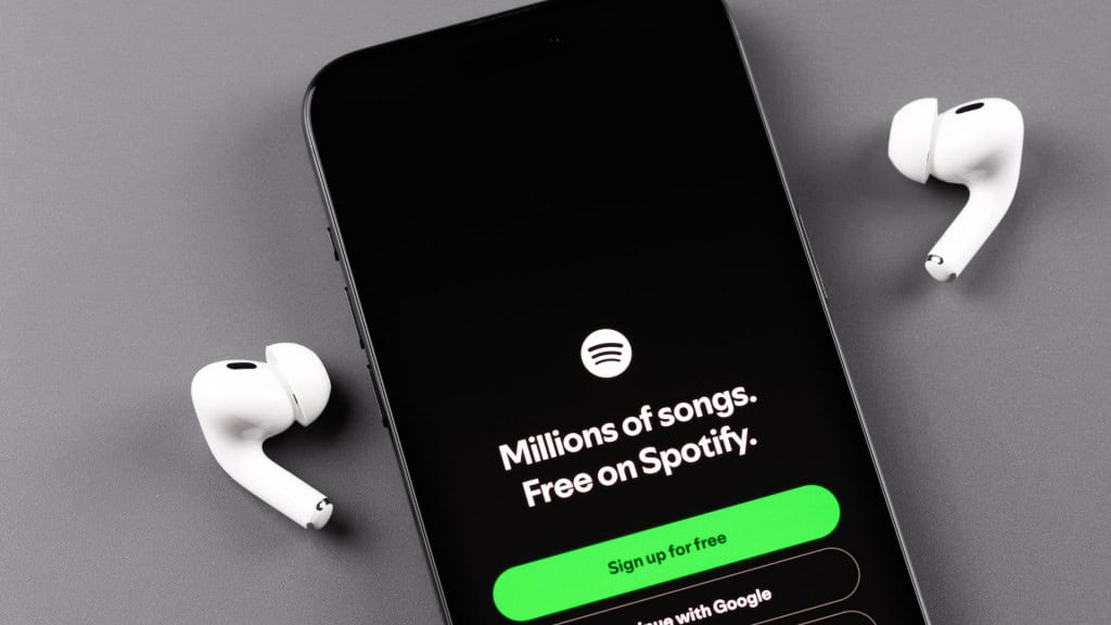 Spotify aplicativo móvel em um iPhone smartphone tela com fones de ouvido Apple AirPods. Spotify - serviço de streaming de áudio online. Batumi, Geórgia - 11 de agosto de 2024