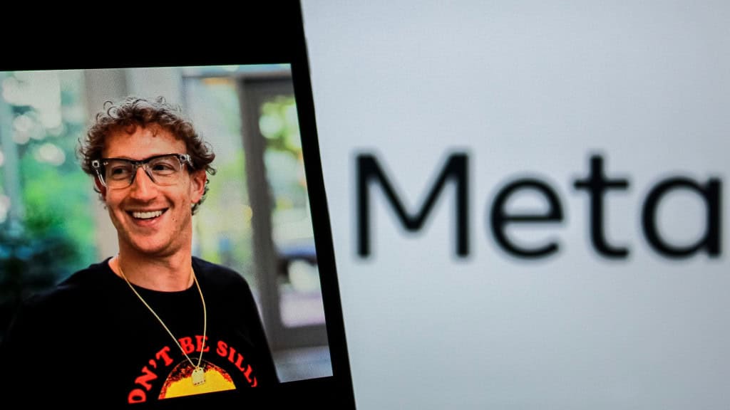 Celular exibindo foto de Mark Zuckerberg colocado em frente tela exibindo logomarca da Meta