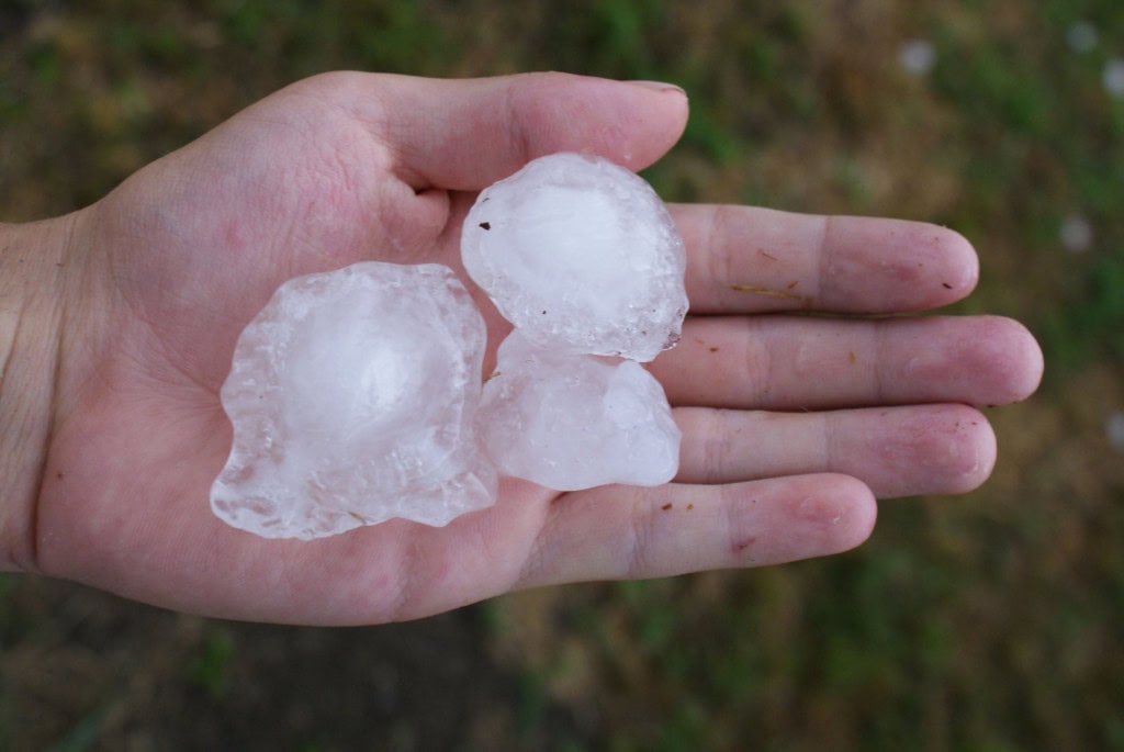 Três grandes pedras de granizo em uma mão humana