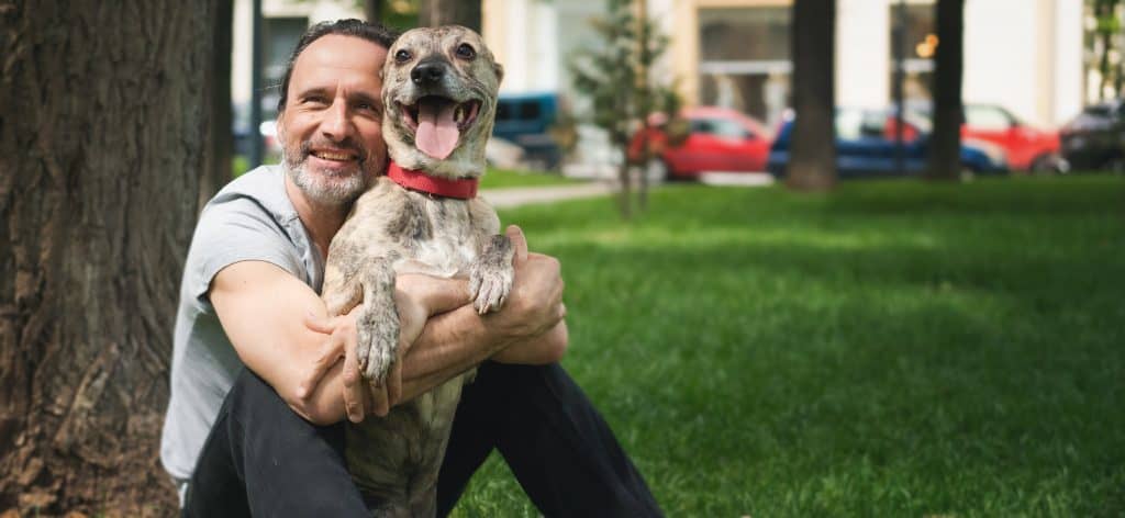 Homem com cerca de 50 anos abraça cachorro