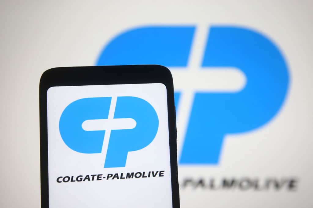 Logo da Colgate-Palmolive ao fundo, desfocado e, à frente, o logo da empresa em um smartphone