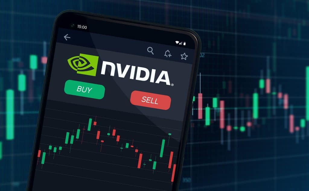 Logo da Nvidia em um smartphone com gráficos de bolsa de valores abaixo e atrás do smartphone